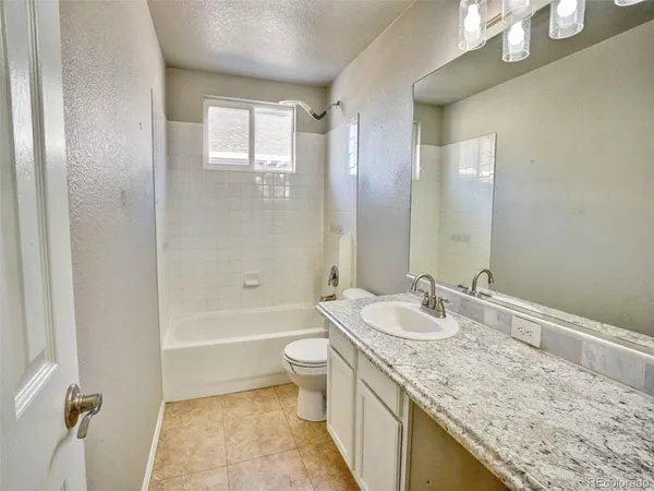 a bathroom with a granite countertop sink a toilet and bathtub