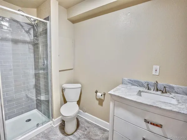 a bathroom with a granite countertop sink toilet and shower