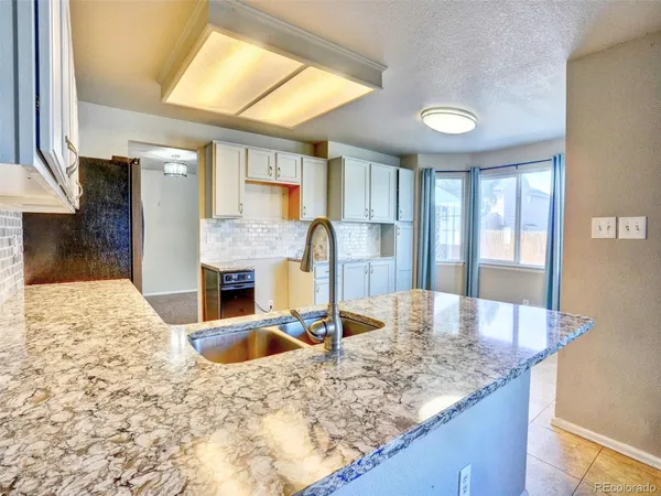 a kitchen with granite countertop a sink and a refrigerator
