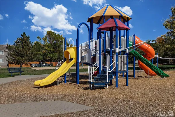 a view of a park with slide and a wooden bench