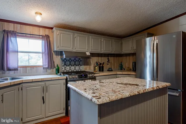 a kitchen with granite countertop a sink stainless steel appliances and cabinets