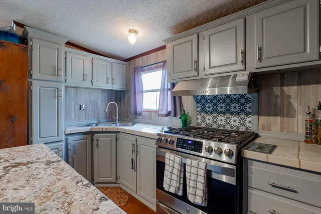 a kitchen with stainless steel appliances granite countertop a stove sink and cabinets