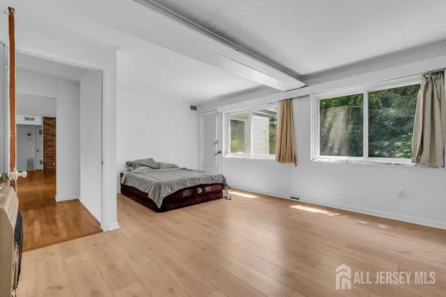 a spacious bedroom with a bed and wooden floor