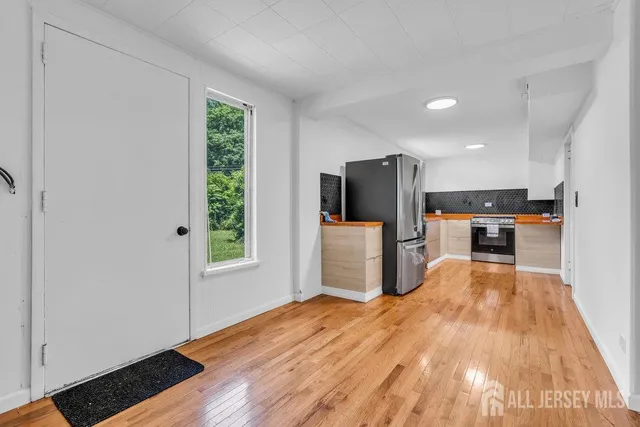a view of a kitchen with wooden floor electronic appliances and windows