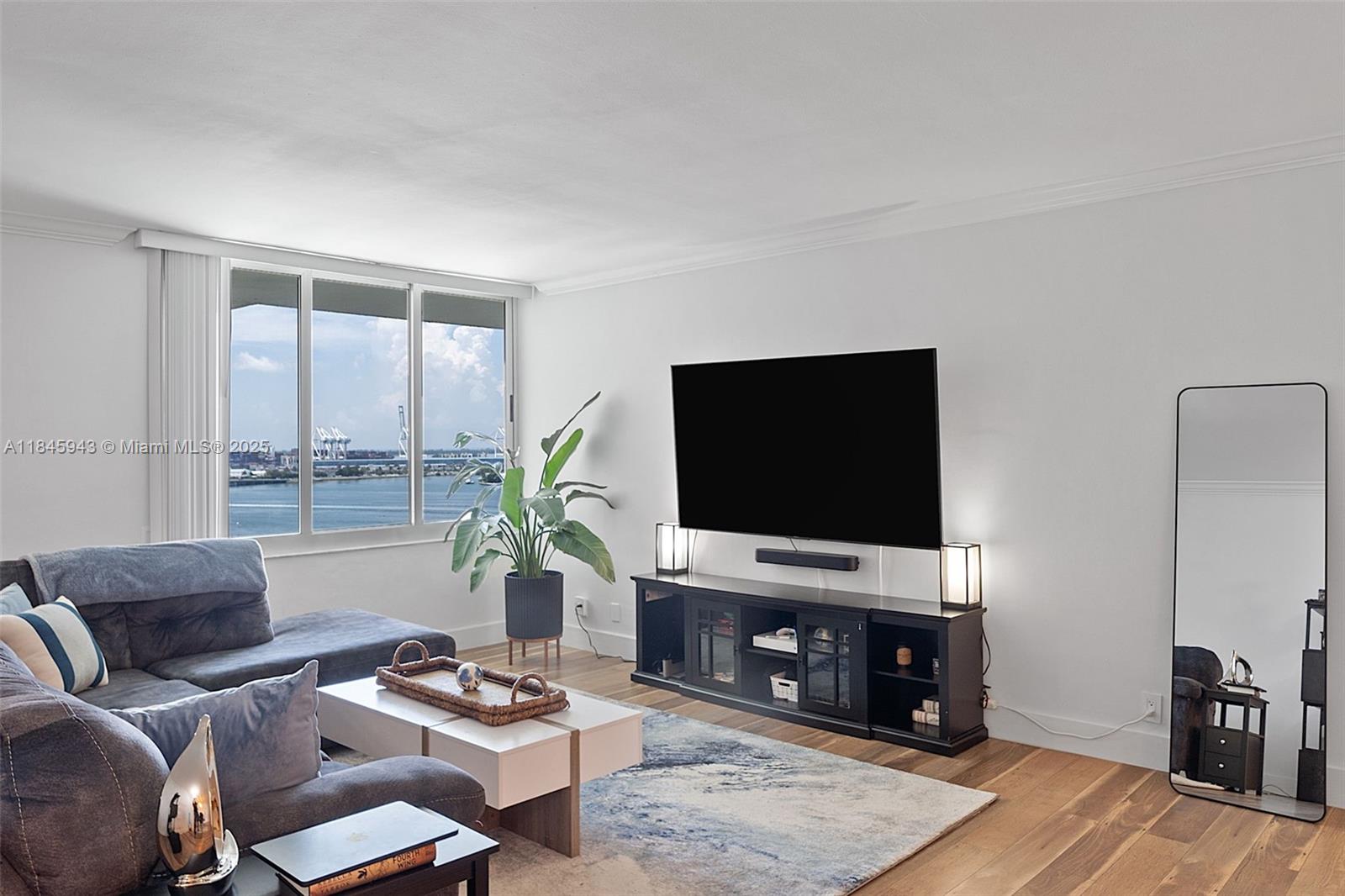 a living room with furniture a flat screen tv and a large window