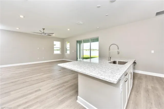 a kitchen with a sink dishwasher and white cabinets with wooden floor