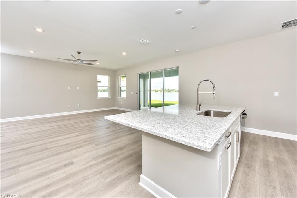 2066 Grove Drive Naples, FL 34120 - Photo 9 of 32 a kitchen with a sink dishwasher and white cabinets with wooden floor