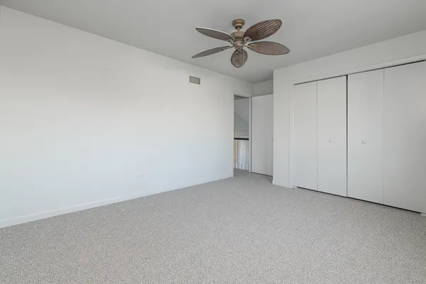 an empty room with a hallway and a ceiling fan