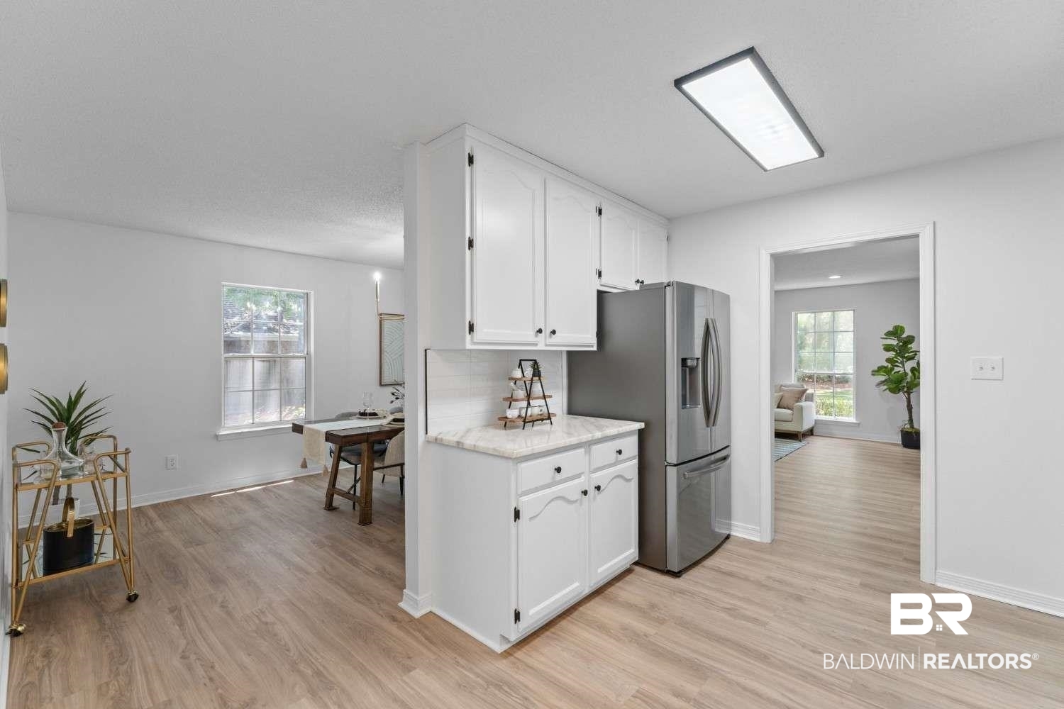 10251 Windmill Road Fairhope, AL 36532 - Photo 26 of 44 Kitchen featuring light wood-type flooring, stainless steel fridge, white cabinets, and plenty of natural light