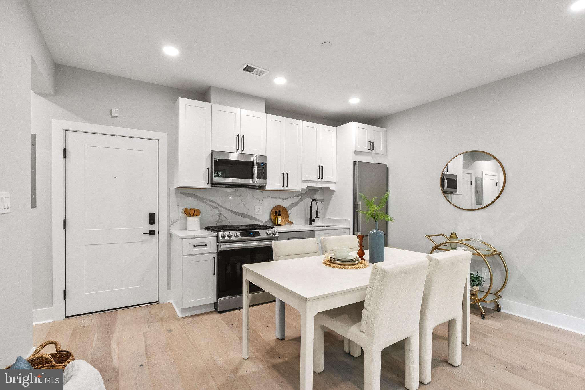 2019 M Street Northeast, Unit 1 Washington, DC 20002 - Photo 2 of 31 a kitchen with stainless steel appliances granite countertop a stove a sink a microwave a refrigerator and white cabinets with wooden floors
