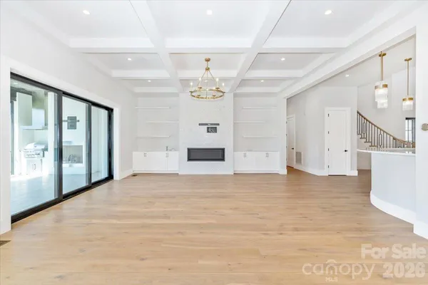 a view of an empty room with a window and a kitchen