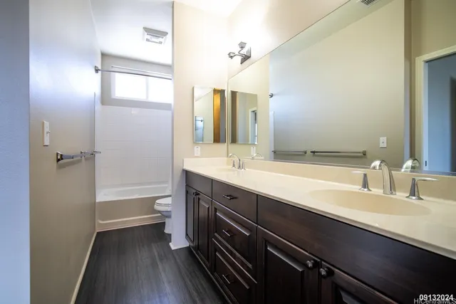 a bathroom with a double vanity sink a toilet and a large mirror