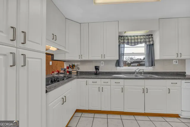 a kitchen with granite countertop a refrigerator a sink and white cabinets