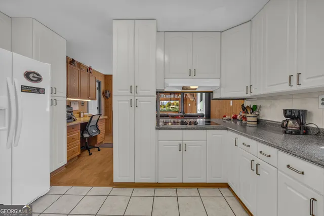 a view of an empty room with wooden floor and a ceiling fan