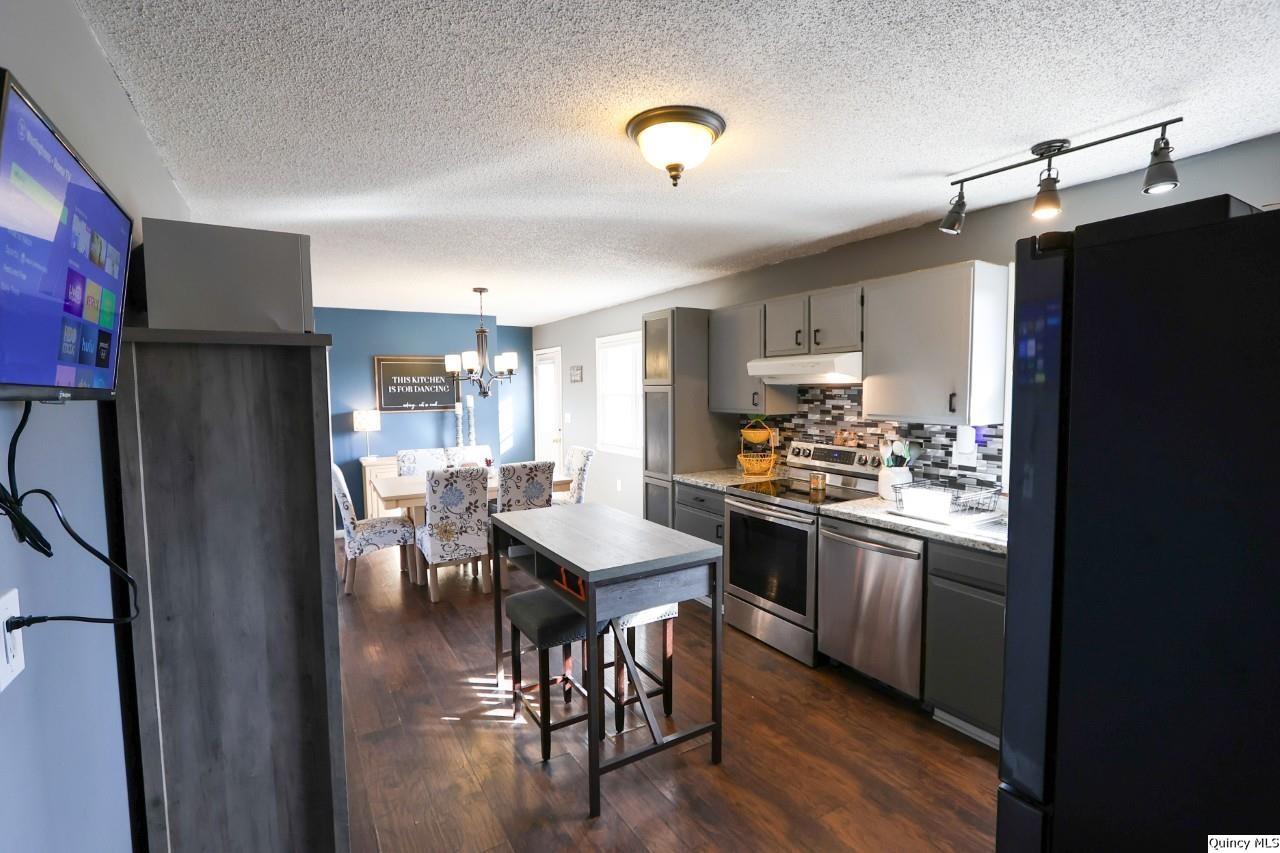 4400 State Street Quincy, IL 62305 - Photo 10 of 31 a kitchen with stainless steel appliances granite countertop a refrigerator a sink dishwasher a stove and a dining table with wooden floor