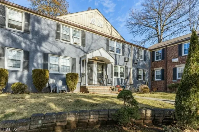 a front view of a building with street and trees