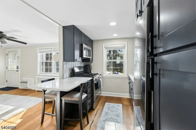 a view of a kitchen with kitchen island a dining table chairs stainless steel appliances and cabinets