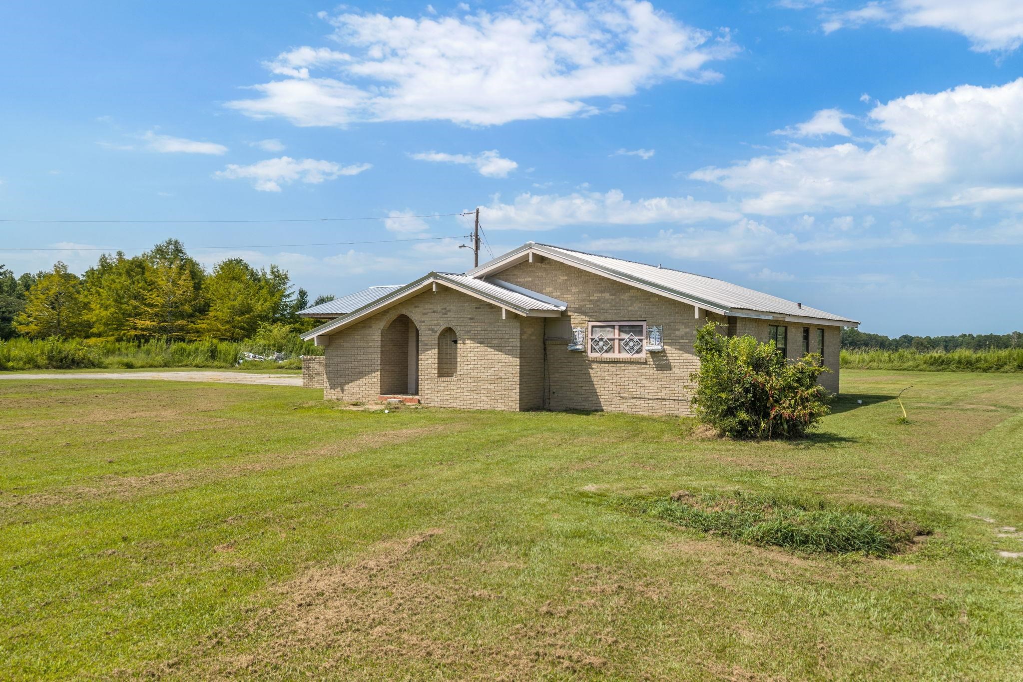 60116 Seminole Road Smithville, MS 38870 - Photo 2 of 38 Brick exterior with a metal roof, arched entry, and expansive surrounding green space