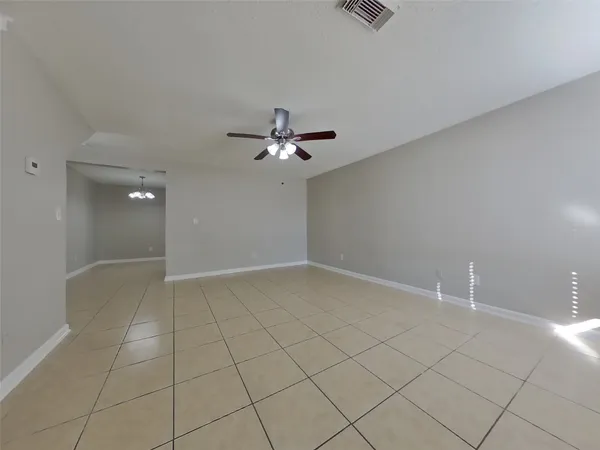 a view of an empty room with a chandelier fan