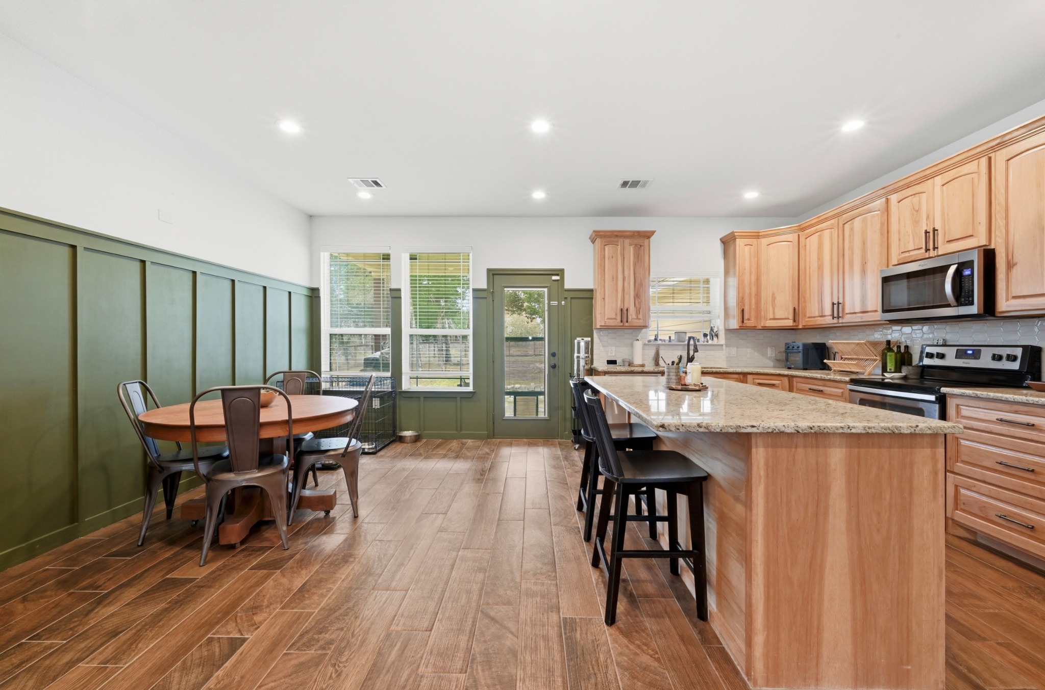 202 Cedar Hills Drive Elgin, TX 78621 - Photo 10 of 37 a kitchen with stainless steel appliances granite countertop a stove a refrigerator a table and chairs with wooden floor