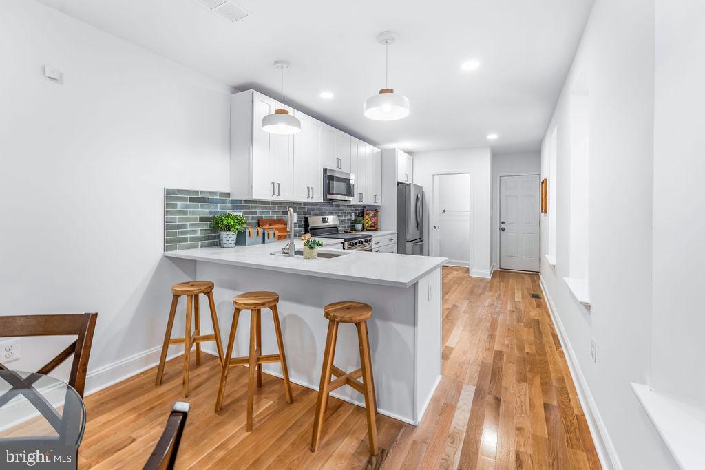 107 South Fulton Avenue Baltimore, MD 21223 - Photo 6 of 36 a kitchen with stainless steel appliances a dining table chairs and wooden floor