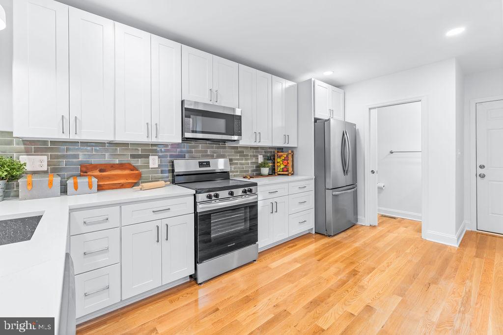 107 South Fulton Avenue Baltimore, MD 21223 - Photo 7 of 36 a kitchen with stainless steel appliances a refrigerator sink and stove
