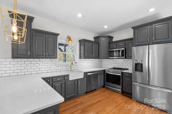 a kitchen with stainless steel appliances granite countertop a sink a stove and a wooden cabinets