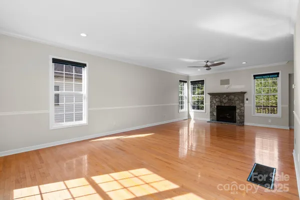 a view of an empty room with wooden floor fireplace and a window