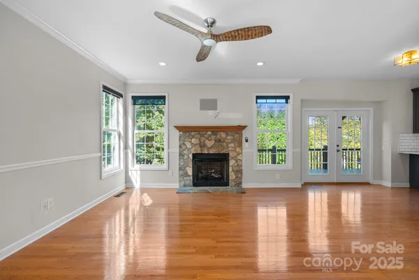 a large kitchen with stainless steel appliances granite countertop a large counter top a stove a sink dishwasher a refrigerator and white cabinets with wooden floor next to windows