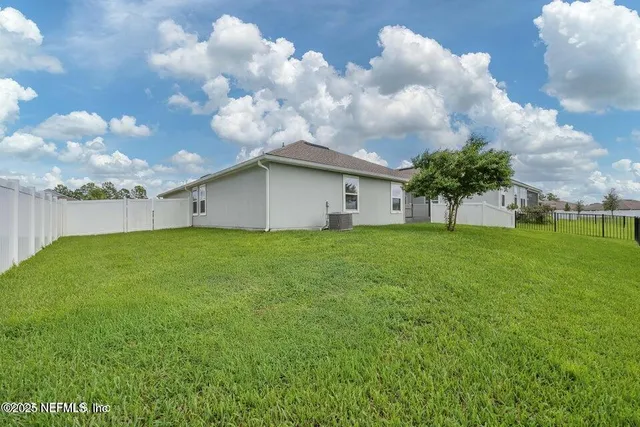 a white house with a big yard and large trees