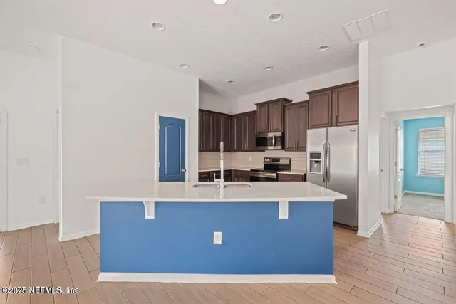 a view of a kitchen with kitchen island a counter top space stainless steel appliances and cabinets