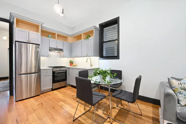 a kitchen with stainless steel appliances kitchen island granite countertop a refrigerator a stove a sink dishwasher a dining table and chairs with wooden floor