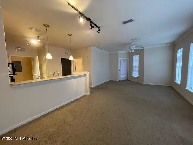 a view of a big room with windows and chandelier fan