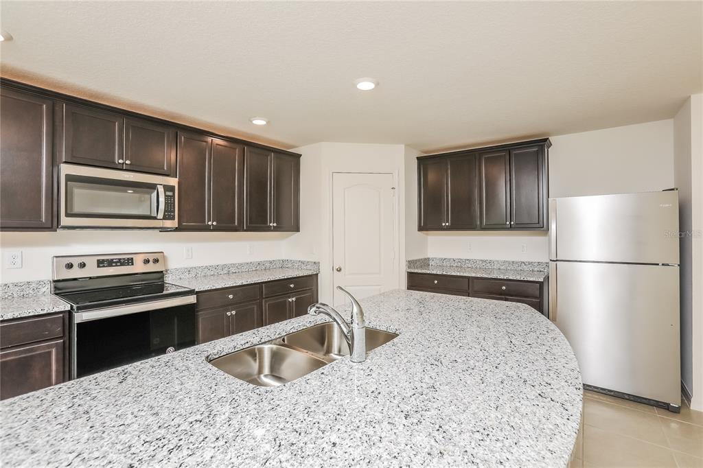 1668 Gopher Tree Street Mascotte, FL 34753 - Photo 4 of 16 a kitchen with stainless steel appliances granite countertop a sink stove and refrigerator