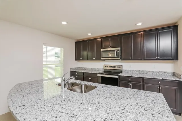 a kitchen with stainless steel appliances granite countertop a sink stove microwave and refrigerator
