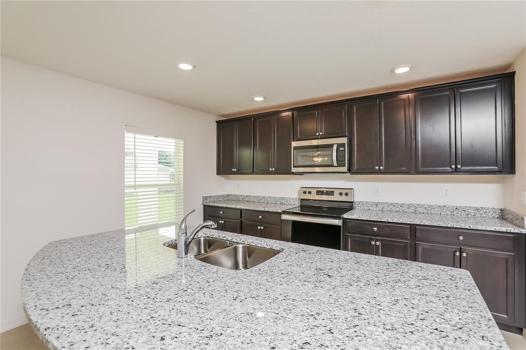 1668 Gopher Tree Street Mascotte, FL 34753 - Photo 5 of 16 a kitchen with stainless steel appliances granite countertop a sink stove microwave and refrigerator