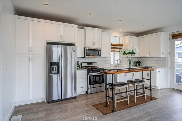 a kitchen with granite countertop a refrigerator stove microwave and cabinets
