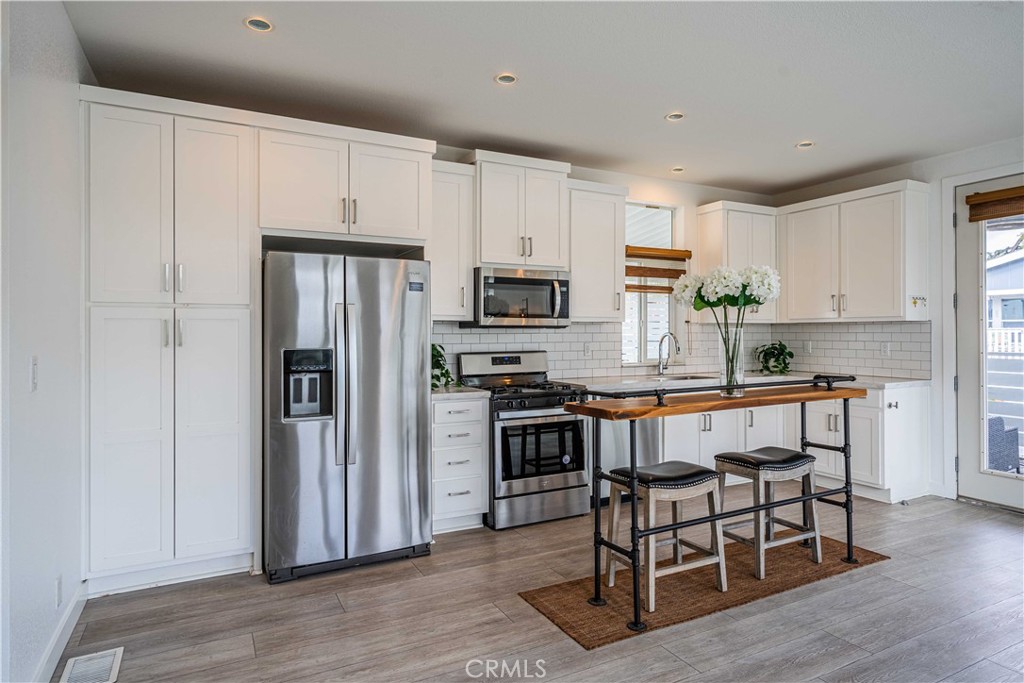 a kitchen with granite countertop a refrigerator stove microwave and cabinets
