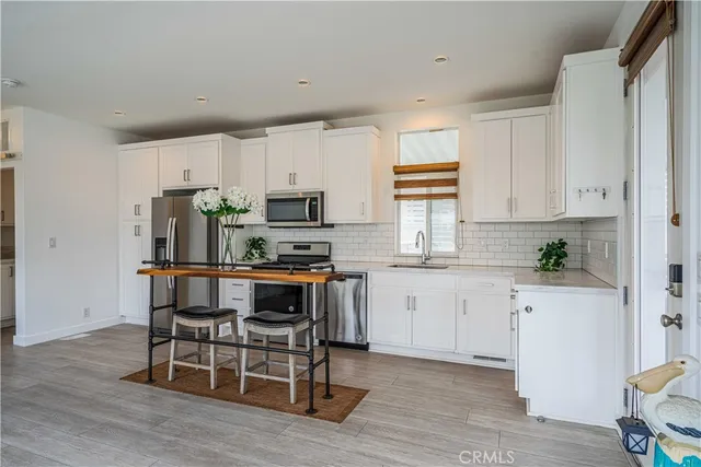 a kitchen with kitchen island granite countertop white cabinets and stainless steel appliances