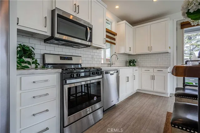 a kitchen with stainless steel appliances white cabinets a stove a sink and a microwave