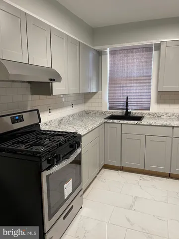 a kitchen with granite countertop a stove sink and cabinets