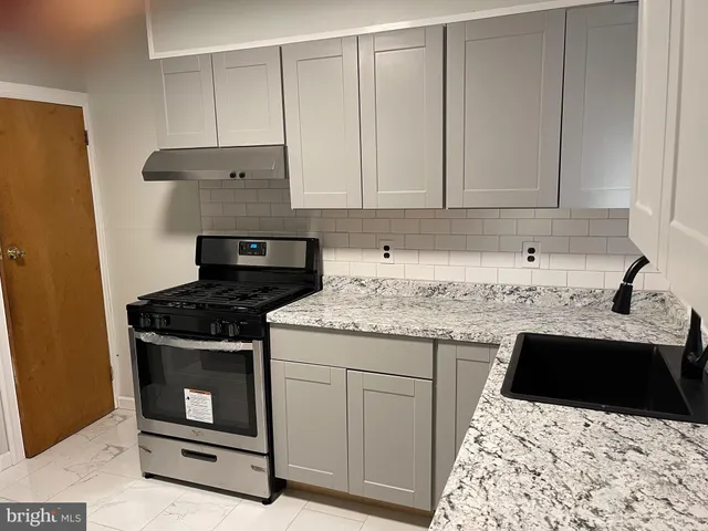 a kitchen with granite countertop a sink stove and cabinets