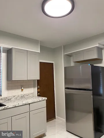 a bathroom with a granite countertop sink and a refrigerator