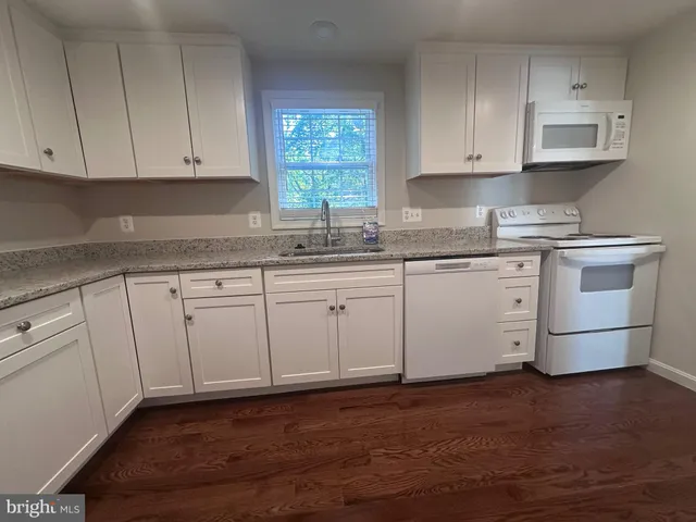 a kitchen with granite countertop white cabinets and a sink