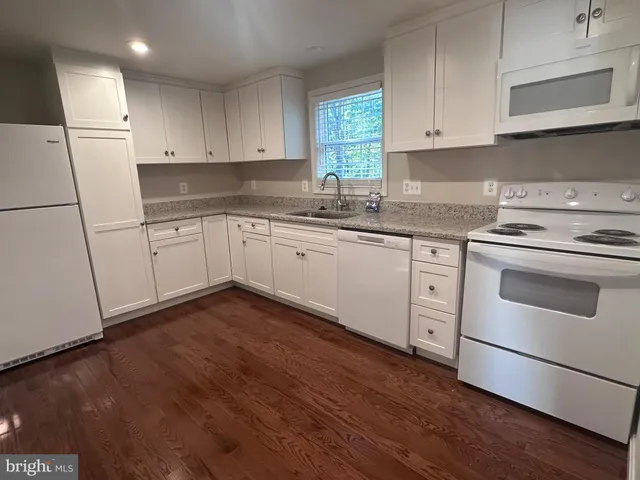 a kitchen with granite countertop white cabinets and white appliances
