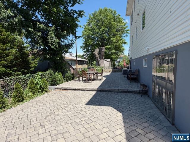 177 Maple Street Fairview, NJ 07022 - Photo 19 of 24 a view of a patio with table and chairs with wooden fence and plants