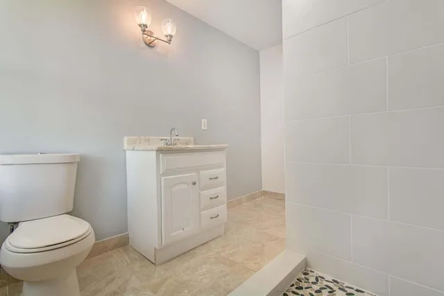 a bathroom with a granite countertop toilet and sink