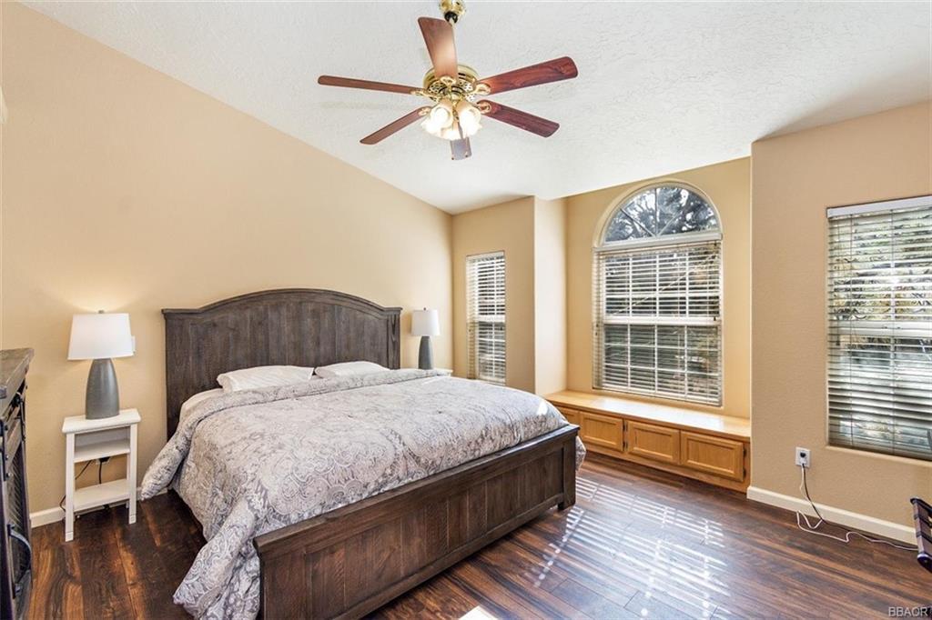 613 Riverside Avenue Sugarloaf, CA 92386 - Photo 11 of 27 a bedroom with a large bed chandelier and a window