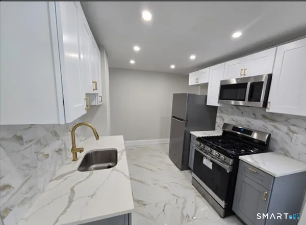 a kitchen with kitchen island stainless steel appliances a sink a stove a microwave a sink and cabinets