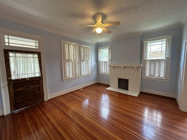 a view of an empty room with wooden floor and a window